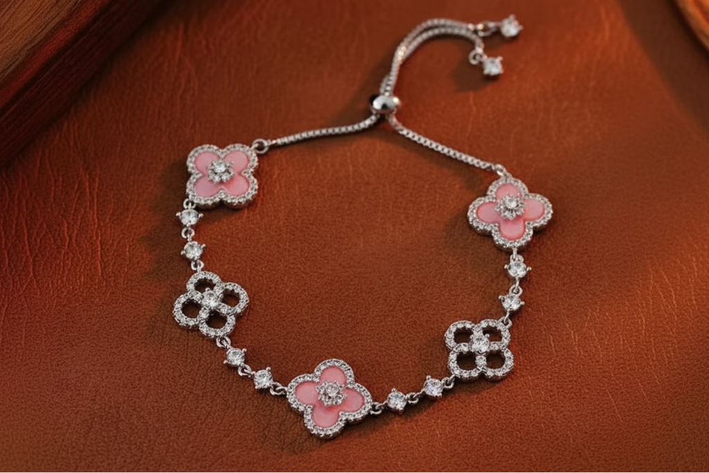 Rose gold bracelet with pink floral charms on a brown leather surface