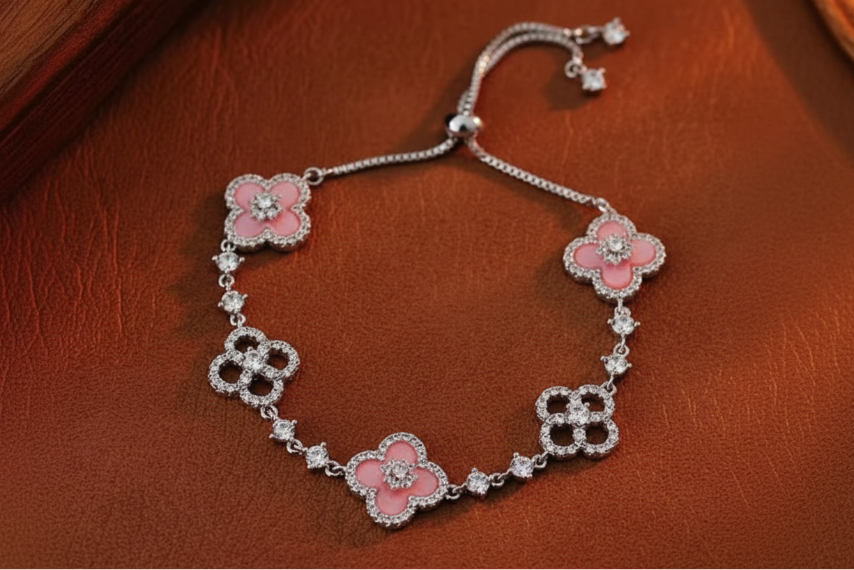 Rose gold bracelet with pink floral charms on a brown leather surface